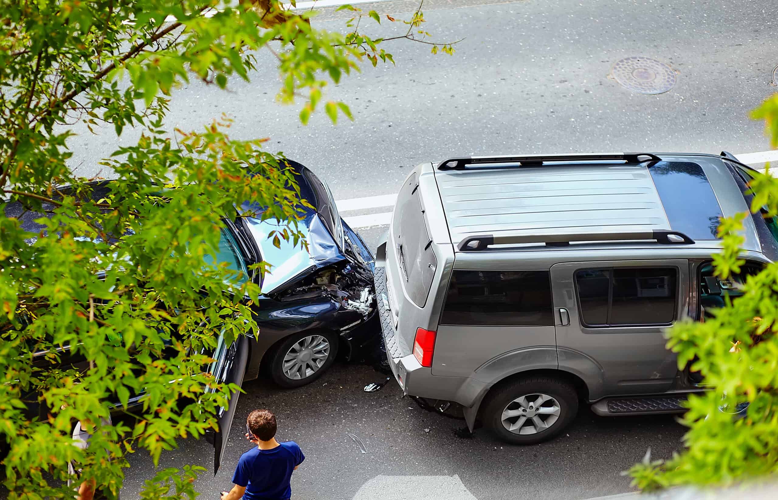 A rear-end collision between a black car and a gray SUV on a busy street